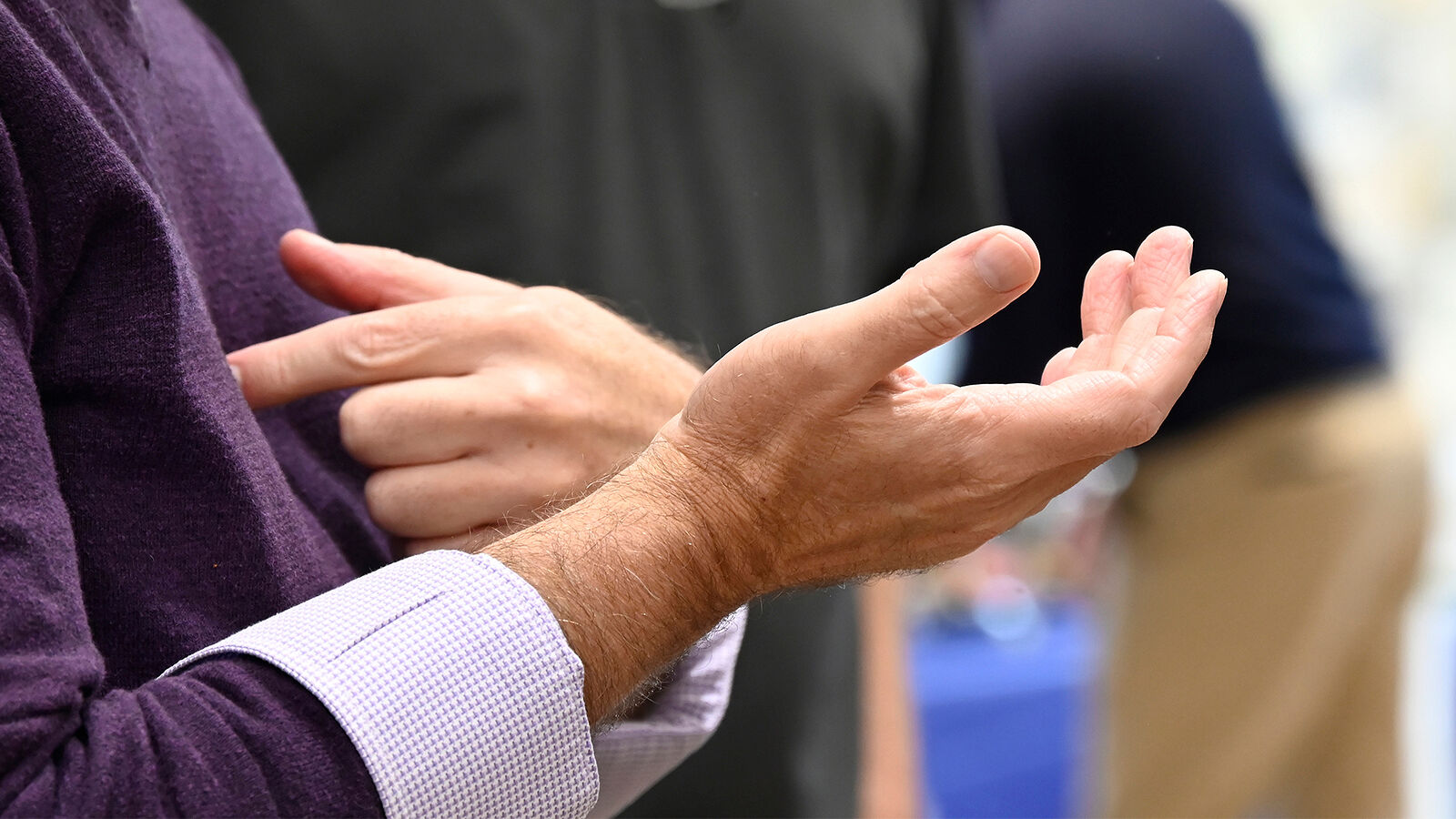 A participant signs in ASL in conversation with other guests.