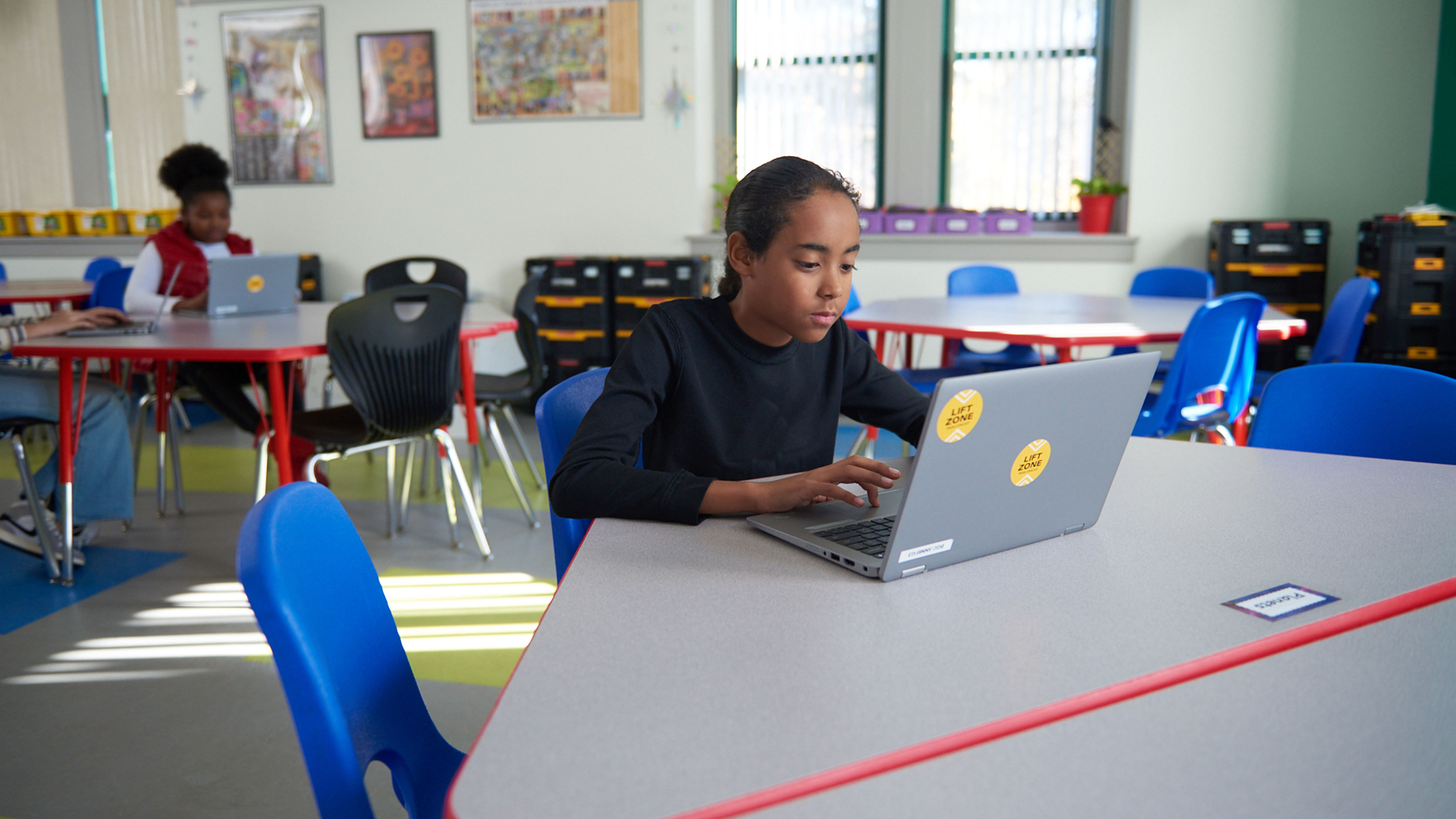 A student sitting at a table using a laptop.