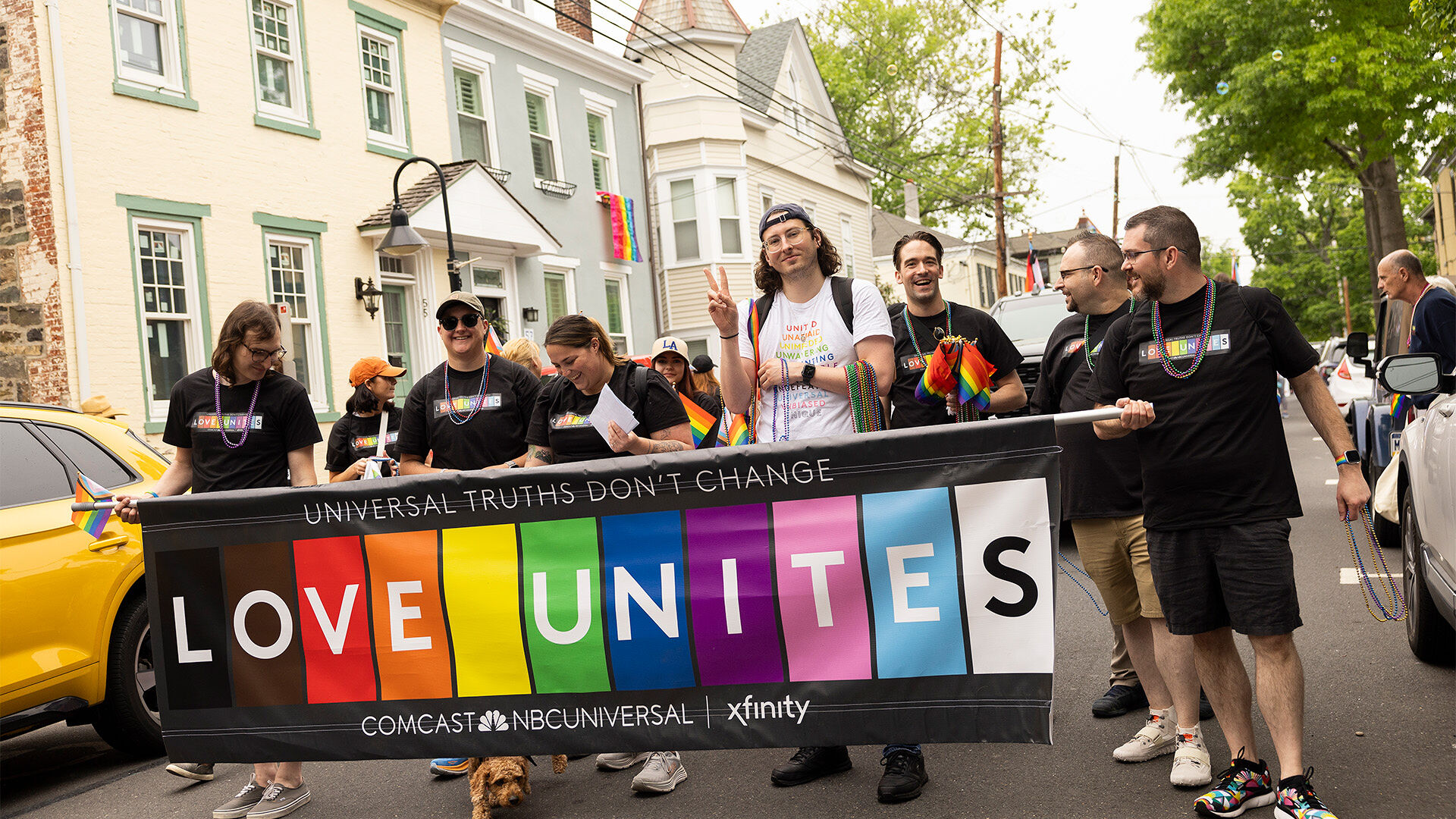 Pride parade participants holding up a 'Love Unites' banner.