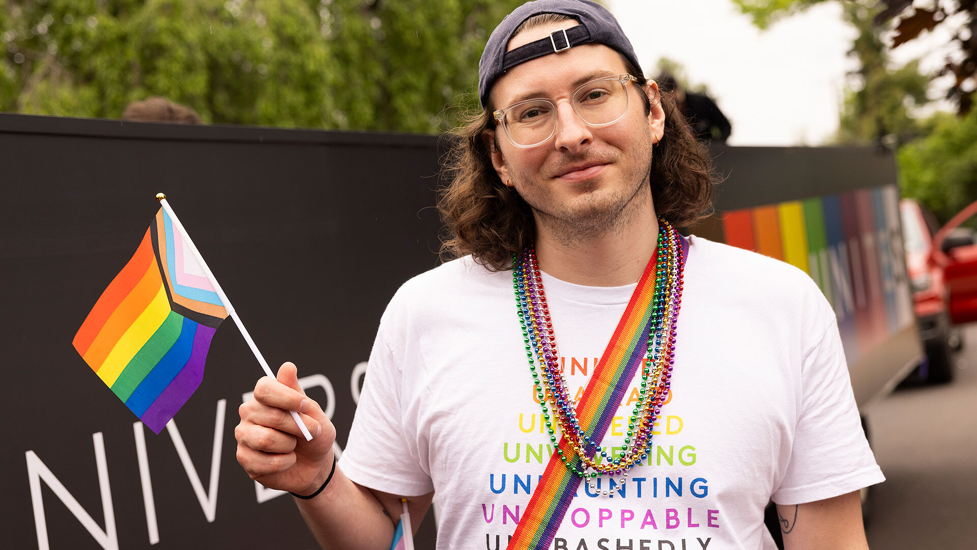 A Pride parade participant holding up a Pride flag.