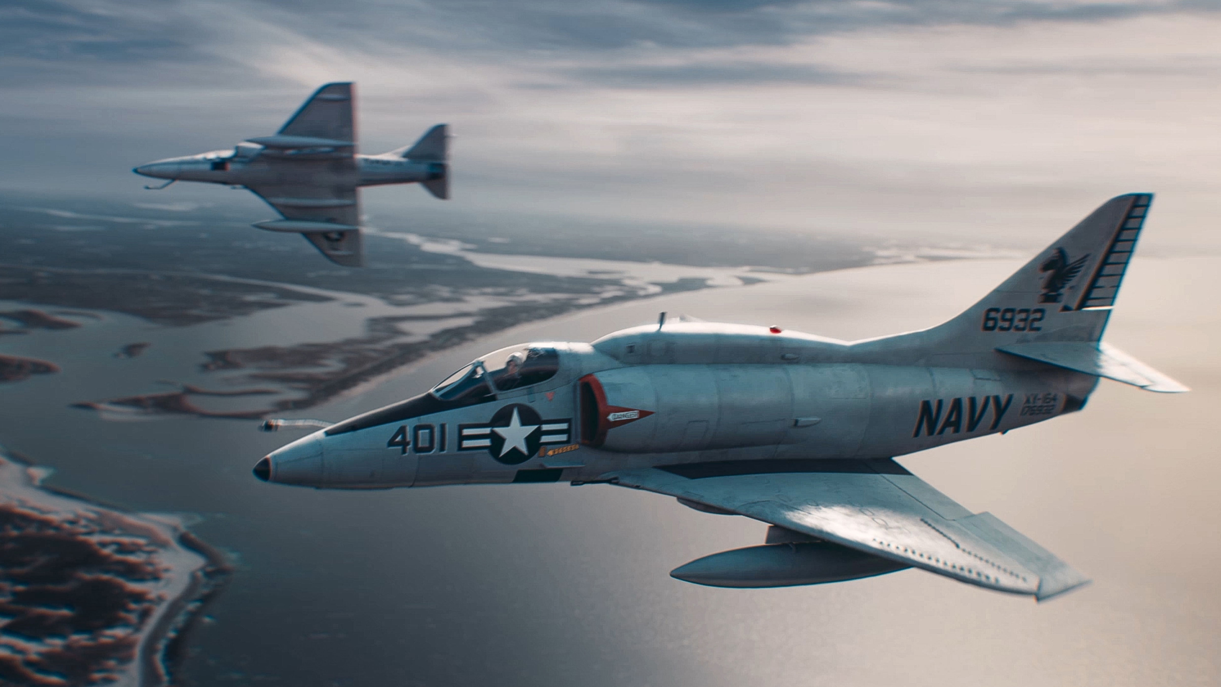 Two Naval planes flying over a body of water.