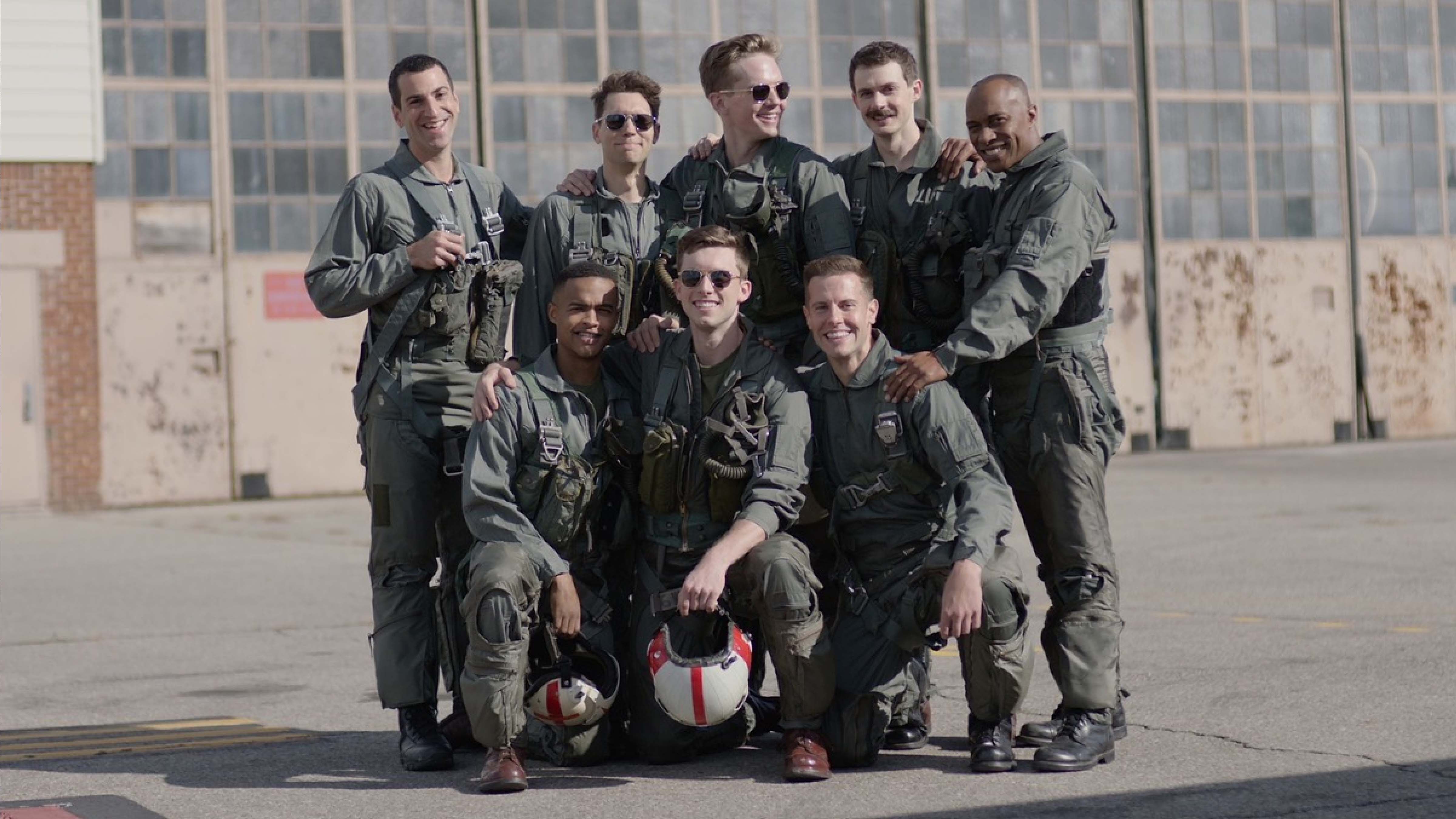 A group of 8 males in army uniforms smiling at the camera.